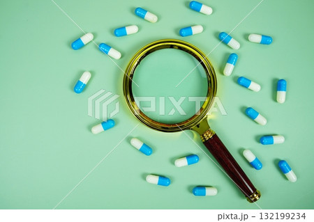 Medicine Capsule and magnifying glass on green background 132199234