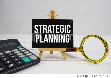 Strategic Planning text with magnifying glass and calculator on wooden background 132199694