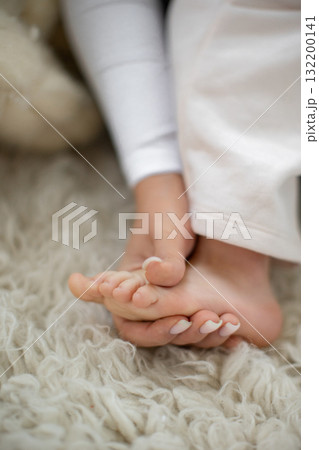 Close-up of a person's feet resting on a soft, white, shaggy rug, with white pants visible. Close-up of a person's feet resting on a soft, white, shaggy rug, with white pants visible. 132200141