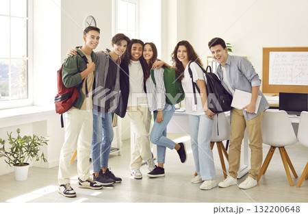 Group of a happy school or college students standing together in classroom and looking at camera. 132200648