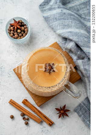 Traditional Indian masala chai tea with milk and spices in a cup on a wooden board  132200655