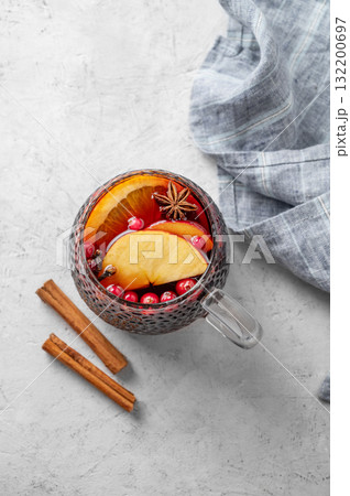 A cup of red mulled wine with spices, orange and apple slices on a light background 132200697