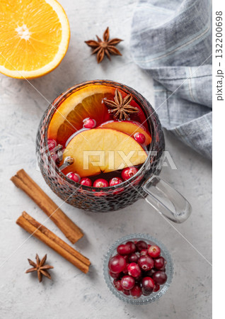 A cup of red mulled wine with spices, orange and apple slices on a light background 132200698