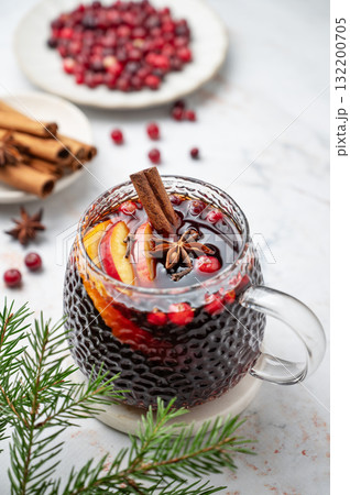 A cup of hot mulled wine with spices, orange and apple slices,  cinnamon sticks 132200705