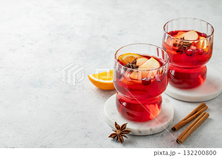 A cranberry drink in a two glasses on a light background with cinnamon and citrus fruit. 132200800