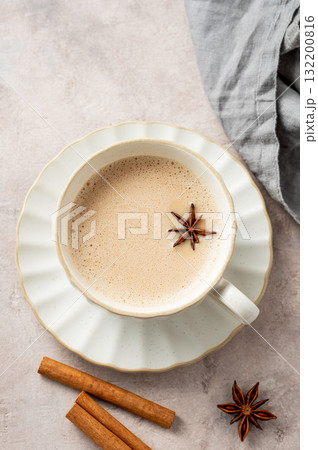 Traditional Indian masala chai tea with milk and spices in a white cup on a light background  132200816