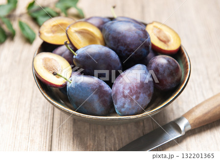 Fresh ripe plums in bowl on wood surface Fresh ripe plums in bowl on wood surface 132201365