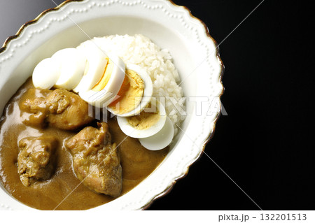 ゆで卵を乗せたチキンカレーを黒背景で撮影 132201513