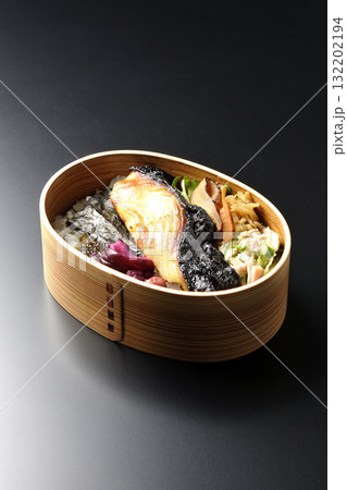 曲げわっぱに入っていて銀鱈の西京焼が乗っている海苔弁当を黒背景で撮影 132202194