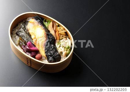 曲げわっぱに入っていて銀鱈の西京焼が乗っている海苔弁当を黒背景で撮影 132202203