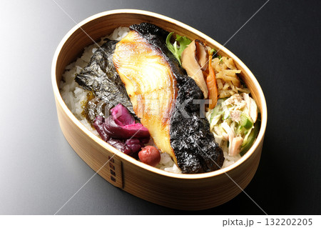 曲げわっぱに入っていて銀鱈の西京焼が乗っている海苔弁当を黒背景で撮影 132202205