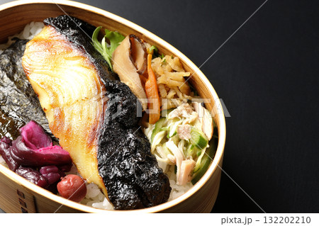 曲げわっぱに入っていて銀鱈の西京焼が乗っている海苔弁当を黒背景で撮影 132202210