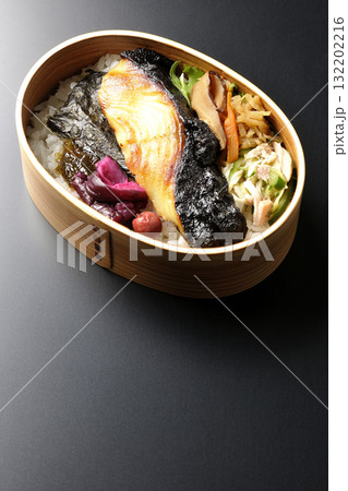 曲げわっぱに入っていて銀鱈の西京焼が乗っている海苔弁当を黒背景で撮影 132202216