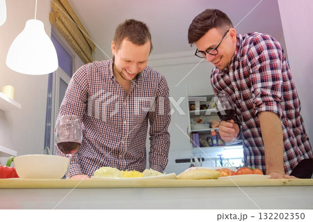 Couple of men gay flirts each other cooking a pizza together and drinking a wine. Couple of men gay flirts each other cooking a pizza together and drinking a wine. 132202350