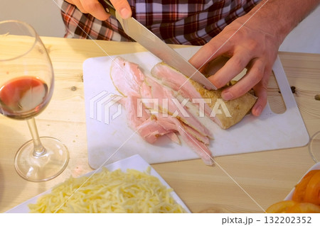 Man cuts smoked brisket, hands close-up. Prepares the ingredients for pizza. 132202352