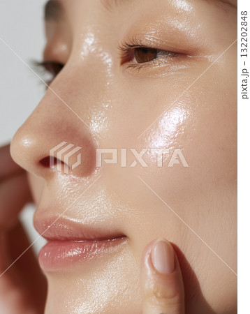 美容液を塗って肌に潤いがある女性の顔のアップ 132202848