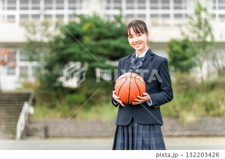 バスケットボールを持って校庭に立つ制服姿の高校生,中学生,小学生の女の子 132203426