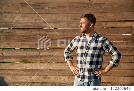 Man in checkered shirt is standing against wooden wall Man in checkered shirt is standing against wooden wall 132203642