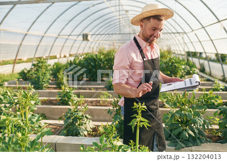 Reading the data. Man in greenhouse is working with plants Reading the data. Man in greenhouse is working with plants 132204013