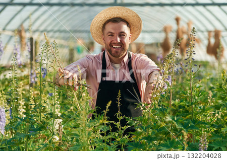 Cheerful facial expression. Man in greenhouse is working with plants Cheerful facial expression. Man in greenhouse is working with plants 132204028