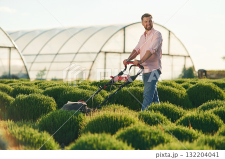 With lawn mower. Adult farmer is outdoors 132204041