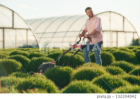 With lawn mower. Adult farmer is outdoors With lawn mower. Adult farmer is outdoors 132204042