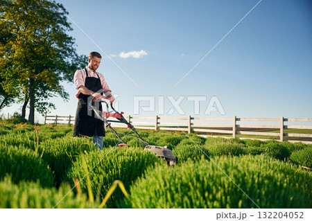 Cleaning the field by using lawn mower. Adult farmer is outdoors Cleaning the field by using lawn mower. Adult farmer is outdoors 132204052