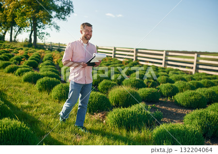Documents in the notepad in hands. Adult farmer is outdoors Documents in the notepad in hands. Adult farmer is outdoors 132204064