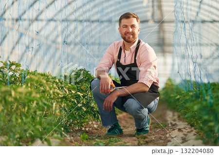 Cheerful facial expression. Man in greenhouse is working with plants 132204080