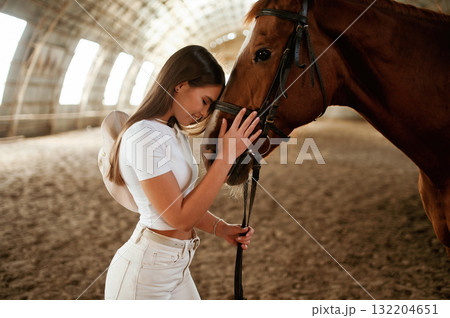 Embracing the animal. Beautiful young woman is with horse indoors 132204651