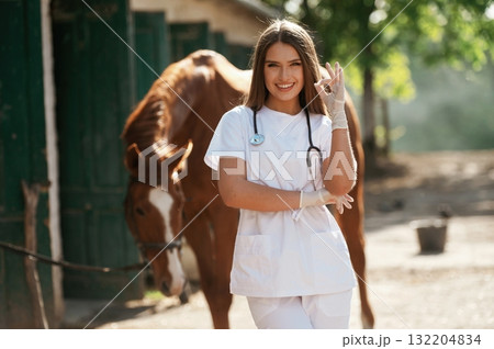Okay, fine hand gesture. Female vet is with horse outdoors at the farm at daytime Okay, fine hand gesture. Female vet is with horse outdoors at the farm at daytime 132204834