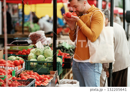 Fresh tomatoes. Handsome man is on the street market or bazaar 132205641