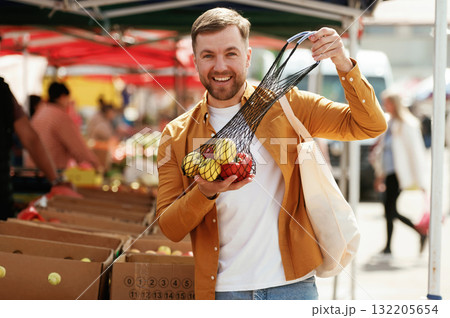 Pepper and apples, smiling. Handsome man is on the street market or bazaar 132205654