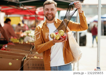 Pepper and apples, smiling. Handsome man is on the street market or bazaar Pepper and apples, smiling. Handsome man is on the street market or bazaar 132205655