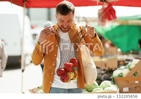 Pepper and apples, smiling. Handsome man is on the street market or bazaar 132205656