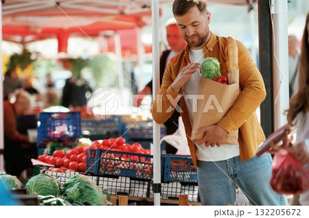 Shopping bag full of products. Handsome man is on the street market or bazaar Shopping bag full of products. Handsome man is on the street market or bazaar 132205672