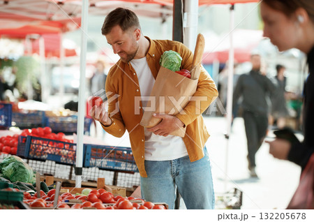 Collection of products in paper bag. Handsome man is on the street market or bazaar Collection of products in paper bag. Handsome man is on the street market or bazaar 132205678
