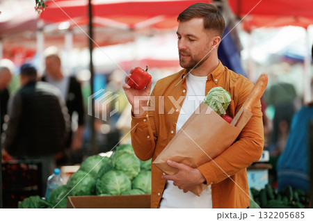 Baguette, pepper and cabbage in bag. Handsome man is on the street market or bazaar 132205685