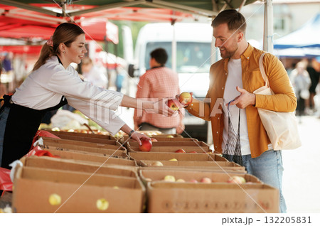 Giving apples. Man is buying products on the street market or bazaar from woman 132205831