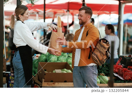Man is buying products on the street market or bazaar from woman Man is buying products on the street market or bazaar from woman 132205844