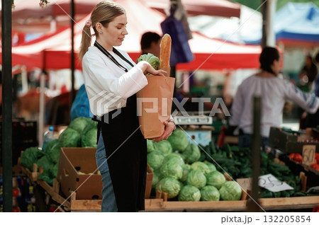 Woman seller at the market with products in a paper bag Woman seller at the market with products in a paper bag 132205854