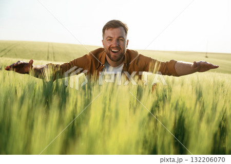 Embracing the growing wheat, smiling. Handsome man is on the agricultural field at daytime 132206070