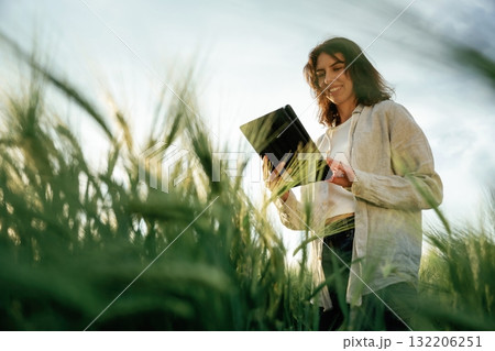 Quality control, with tablet. Woman in white is on the agricultural wheat field 132206251