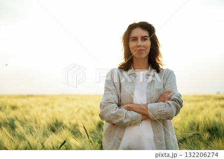 Standing with arms crossed. Woman in white is on the agricultural wheat field 132206274