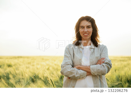Standing with arms crossed. Woman in white is on the agricultural wheat field Standing with arms crossed. Woman in white is on the agricultural wheat field 132206276