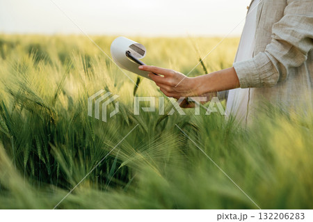 Notepad with documents in hands. Woman in white is on the agricultural wheat field Notepad with documents in hands. Woman in white is on the agricultural wheat field 132206283