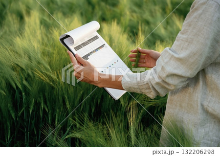 Reading the documents. Woman in white is on the agricultural wheat field Reading the documents. Woman in white is on the agricultural wheat field 132206298