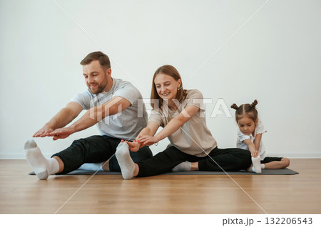 Family of mother, father and daughter are doing yoga at home Family of mother, father and daughter are doing yoga at home 132206543