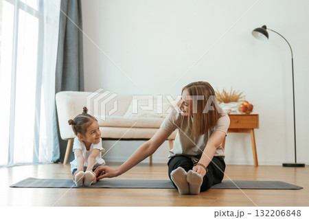 Young woman with little girl are doing yoga at home 132206848