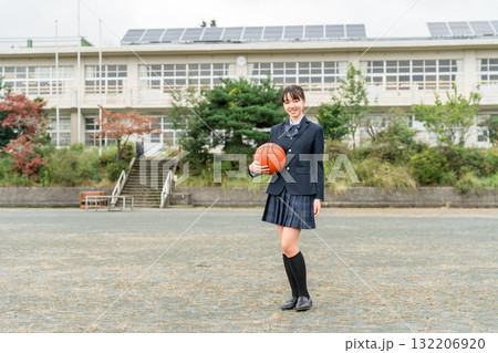 バスケットボールを持って校庭に立つ制服姿の高校生,中学生,小学生の女の子 バスケットボールを持って校庭に立つ制服姿の高校生,中学生,小学生の女の子 132206920